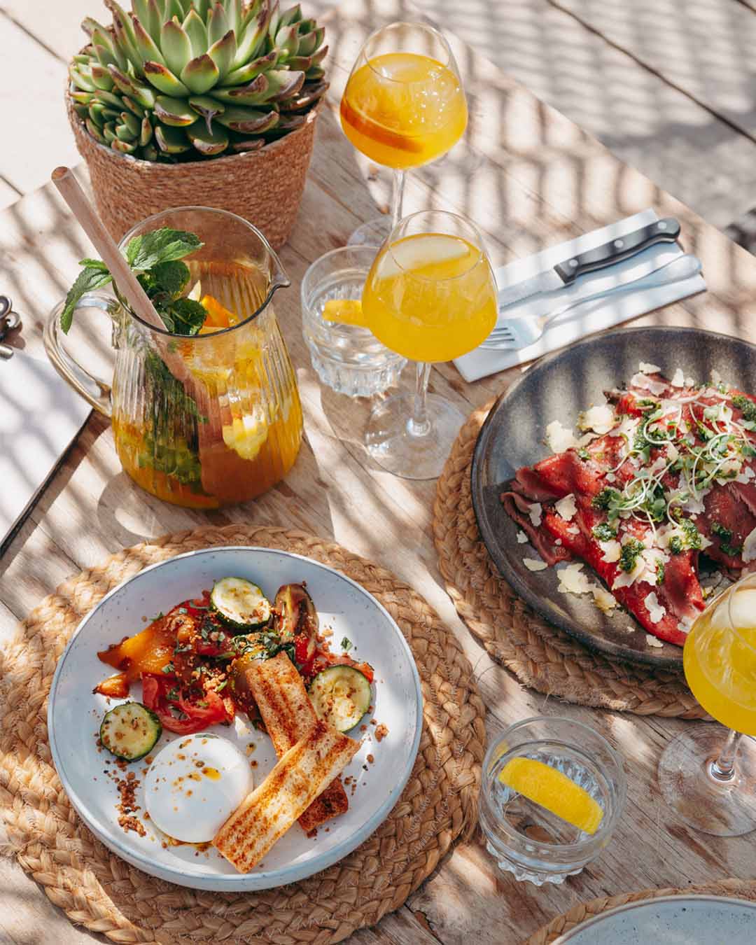Gedekte tafel van bovenaf met diverse lunch-gerechten en drankjes bij Branding Noordwijk
