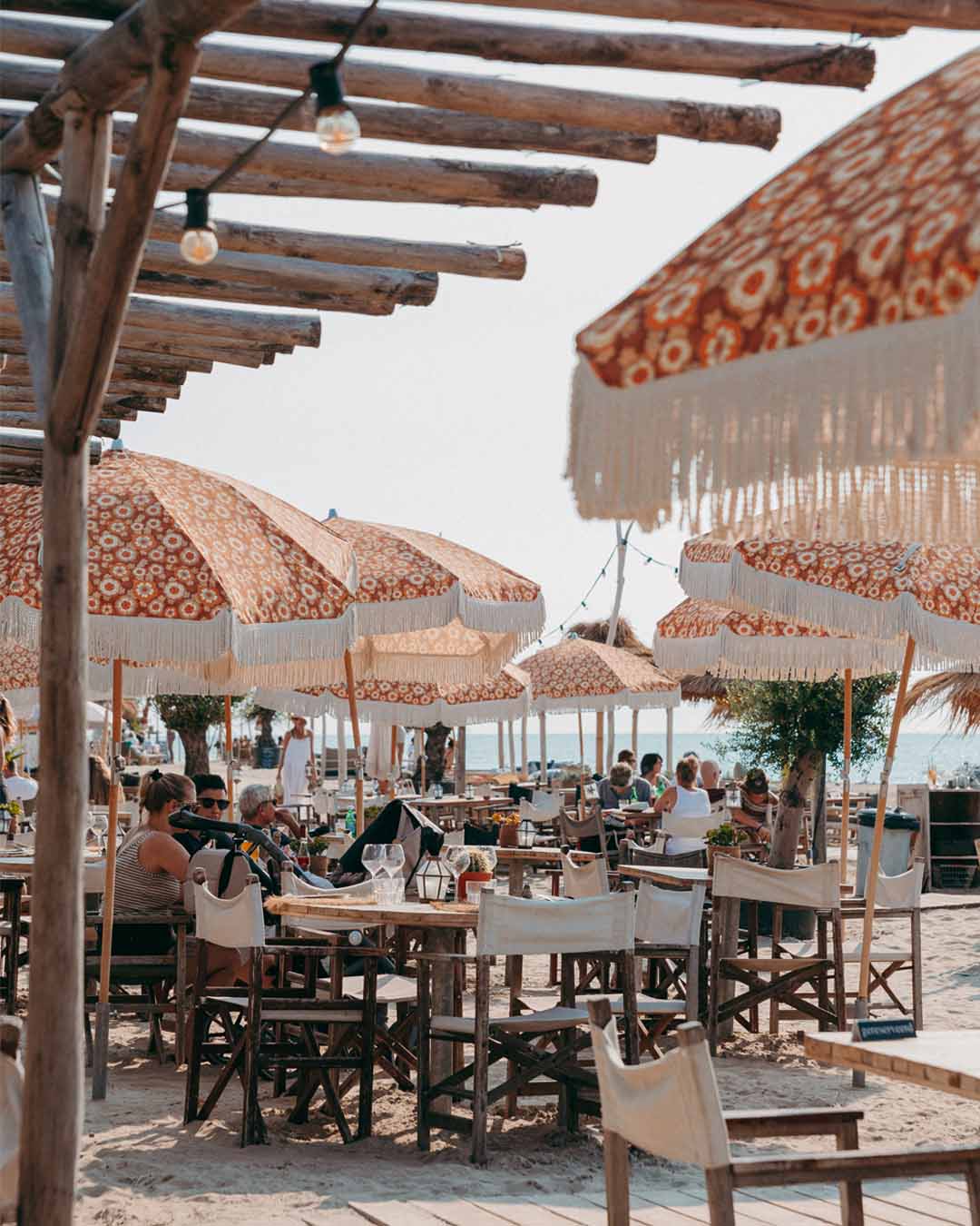 Exterieurshot van een terras met tafels onder parasols bij Kayuca Zandvoort