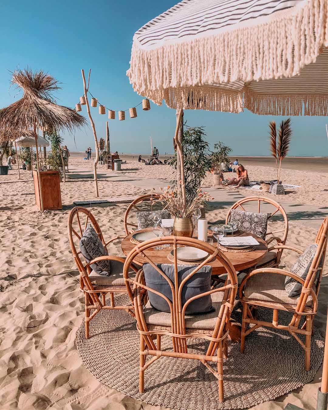 Ingedekte tafel in het zand met stoelen van Ibiza Outdoor onder een parasol