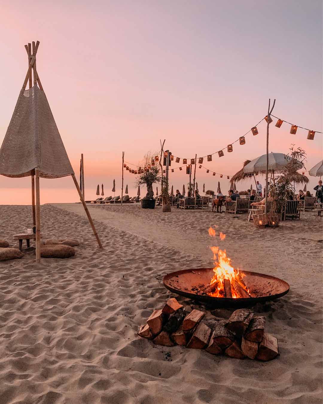 Vuurschaal in het zand voor oranje lucht met zonsondergang voor het terras