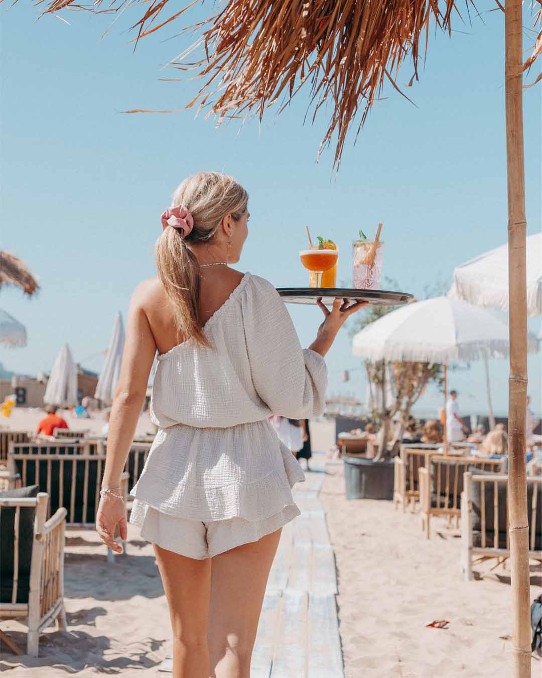 Meisje met dienblad met cocktails lopend over zonnig terras