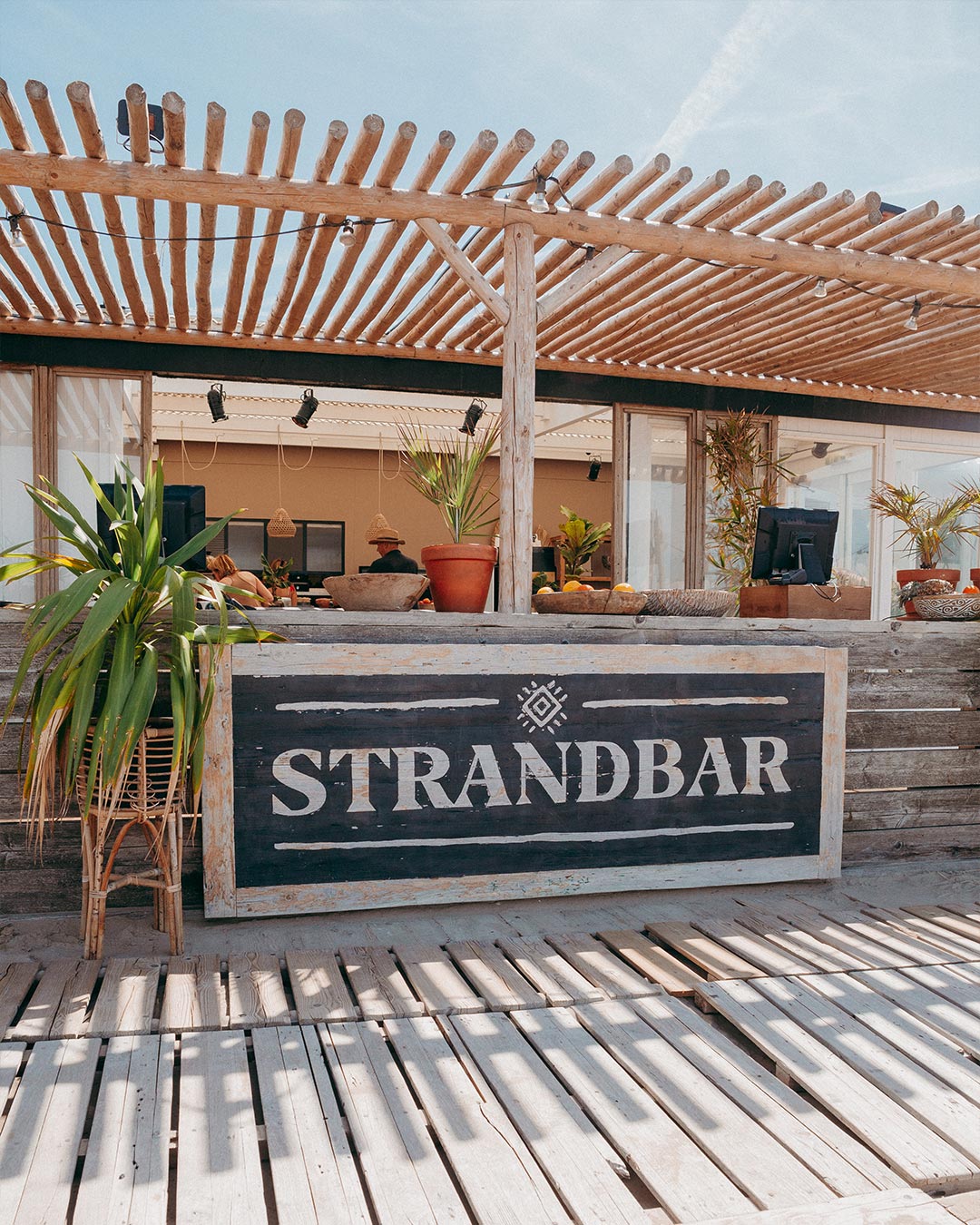 Exterieurfoto van de strandbar met rotan dakafdekking en groene planten